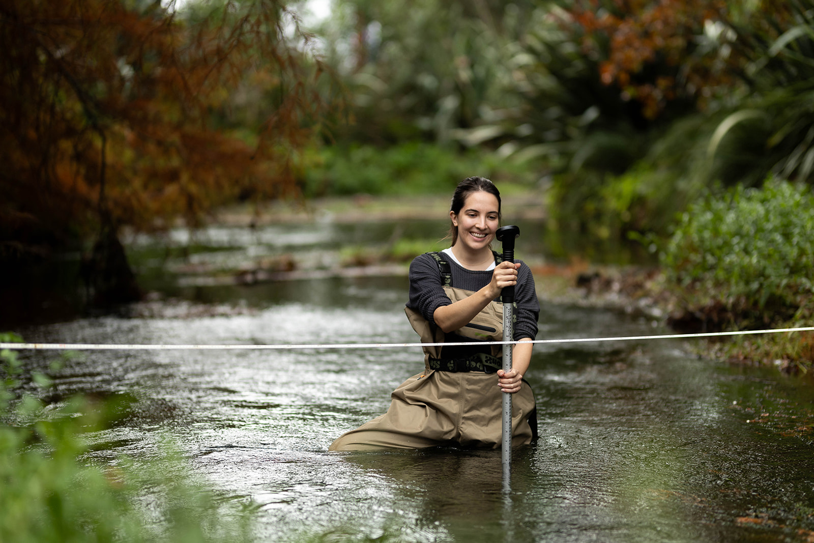 Mathilde Faraud performing investigations in a waist-deep river - Hydrogeology Earthtech Consulting